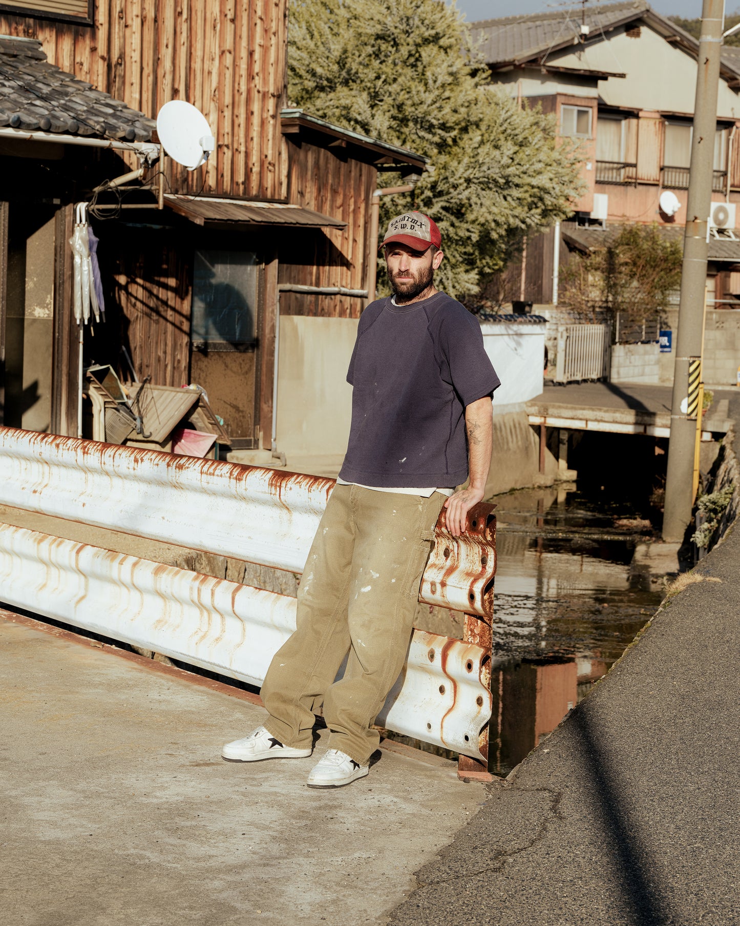 SWJPのS/S Sweatshirtを着た男性が屋外でリラックス。ヴィンテージ感のあるスウェットシャツとワークパンツの組み合わせ。